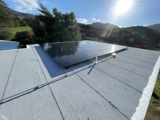 Rooftop solar panels with hills in the background