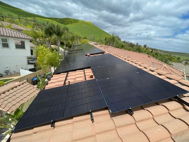 Solar panels on a tiled roof overlooking a residential neighborhood